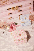 Decorative jewelry box with floral patterns on a table with glasses of pink champagne and a pink bow.